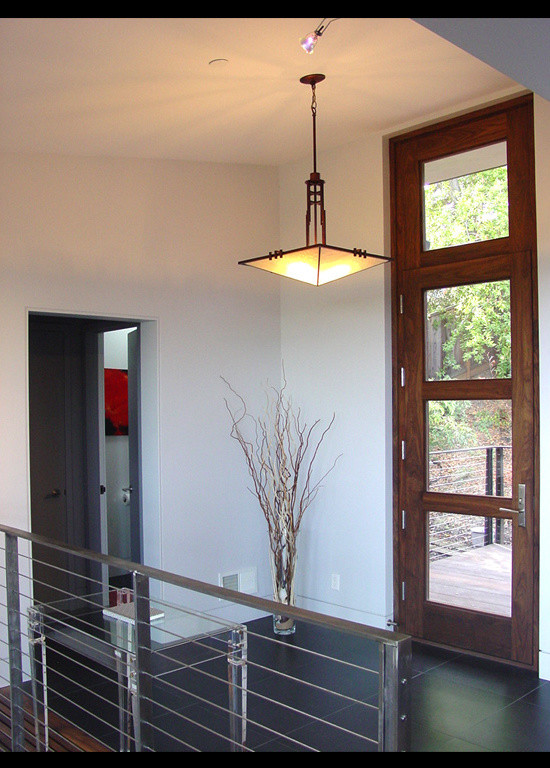 Cette image montre une porte d'entrée minimaliste de taille moyenne avec un mur blanc, un sol en carrelage de porcelaine, une porte simple, une porte en bois foncé, un sol noir et un plafond voûté.