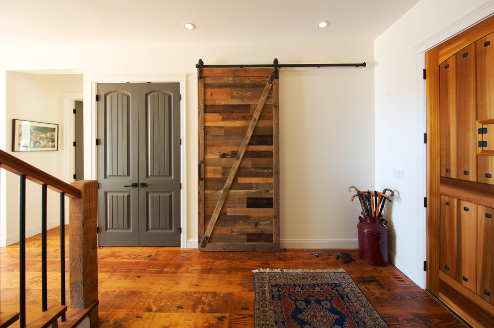 Foto di una piccola porta d'ingresso rustica con pareti bianche, pavimento in legno massello medio, una porta a pivot e una porta in legno bruno