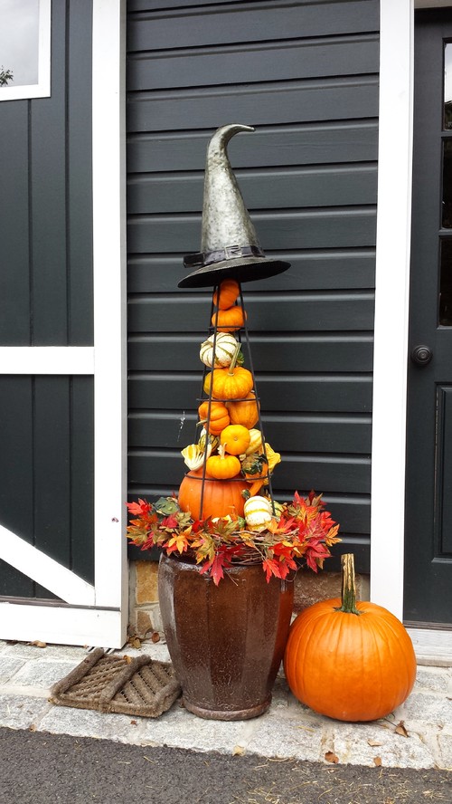 Assorted pumpkins are placed into a garden obelisk and used as a fall porch planter.