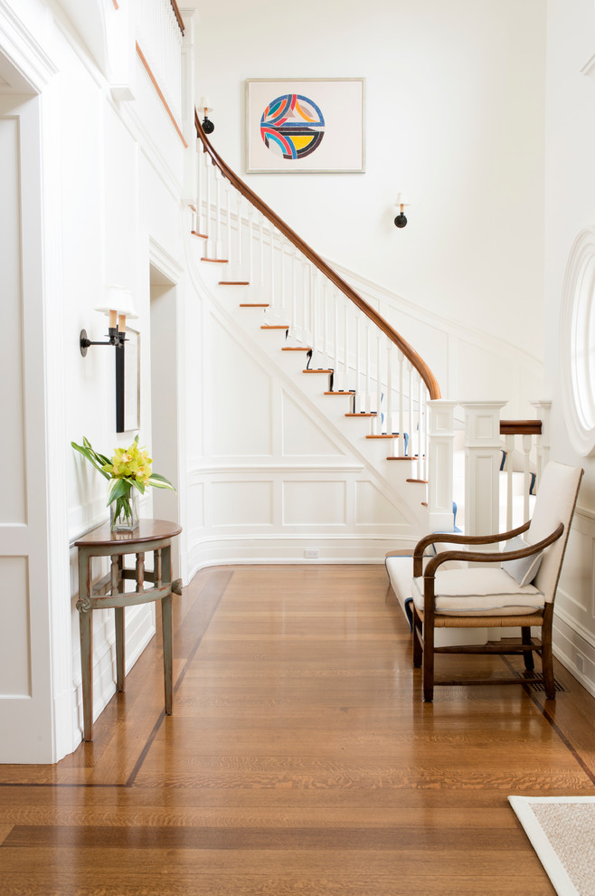 Example of a mid-sized classic medium tone wood floor foyer design in New York with white walls