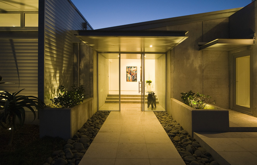 Photo of a contemporary entrance in Auckland with a single front door, a glass front door and feature lighting.