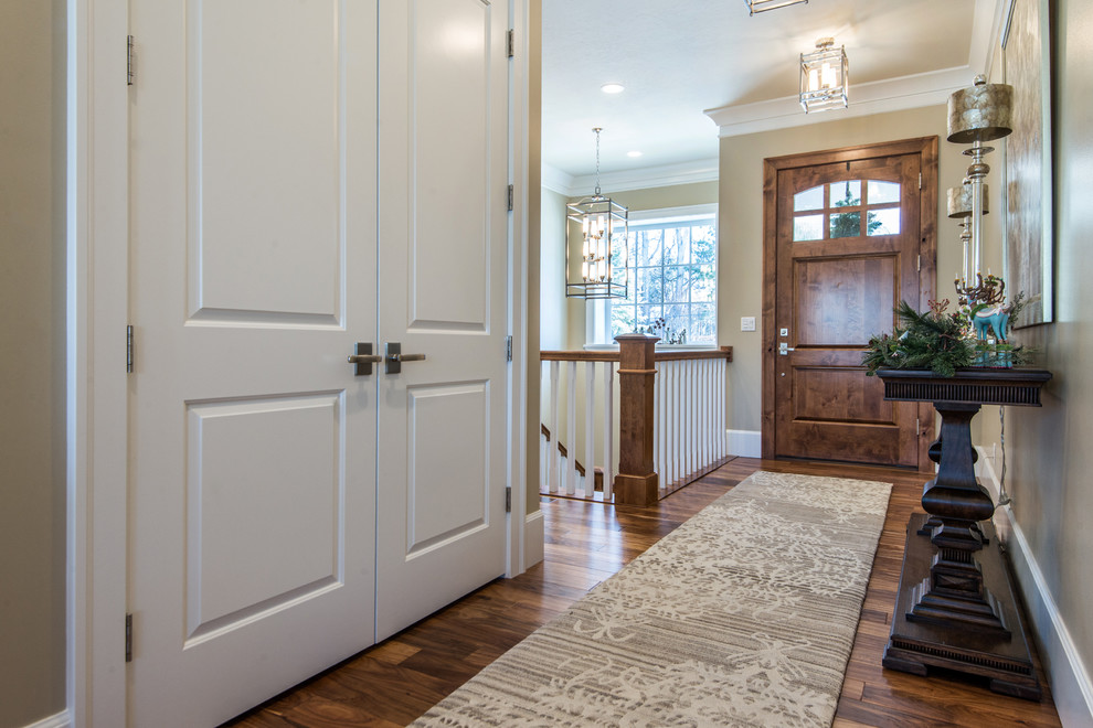 Diseño de entrada de estilo americano de tamaño medio con paredes beige, suelo de madera en tonos medios, puerta simple y puerta de madera en tonos medios