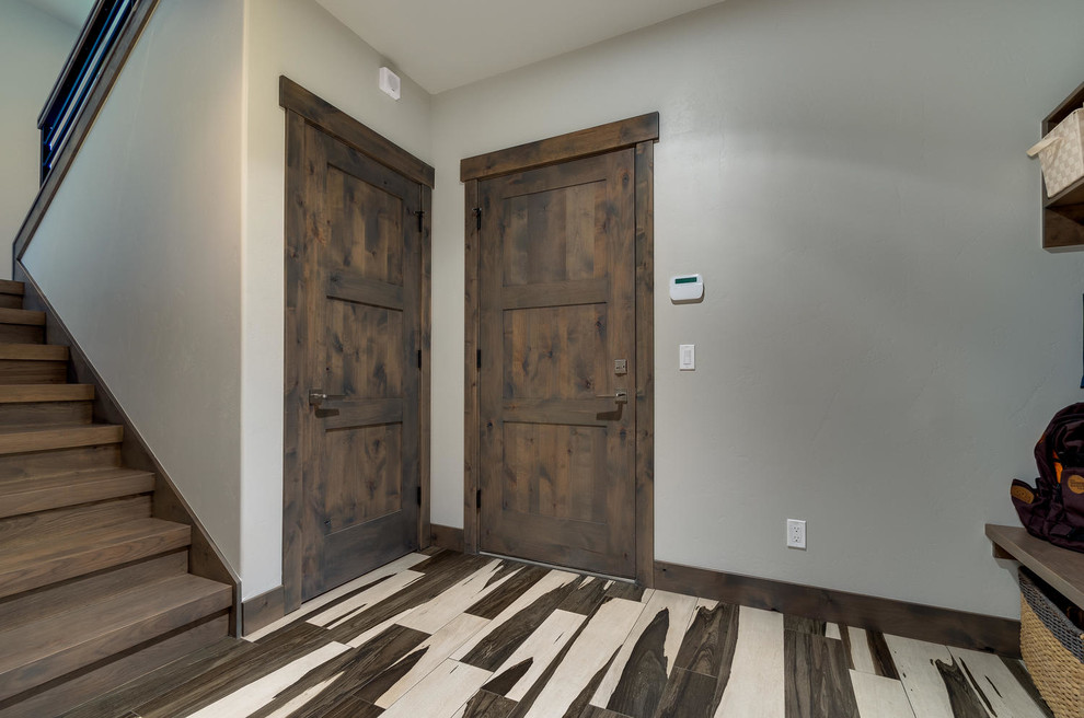 Cette image montre une entrée design de taille moyenne avec un vestiaire, un mur blanc, parquet clair, une porte en bois brun et une porte simple.