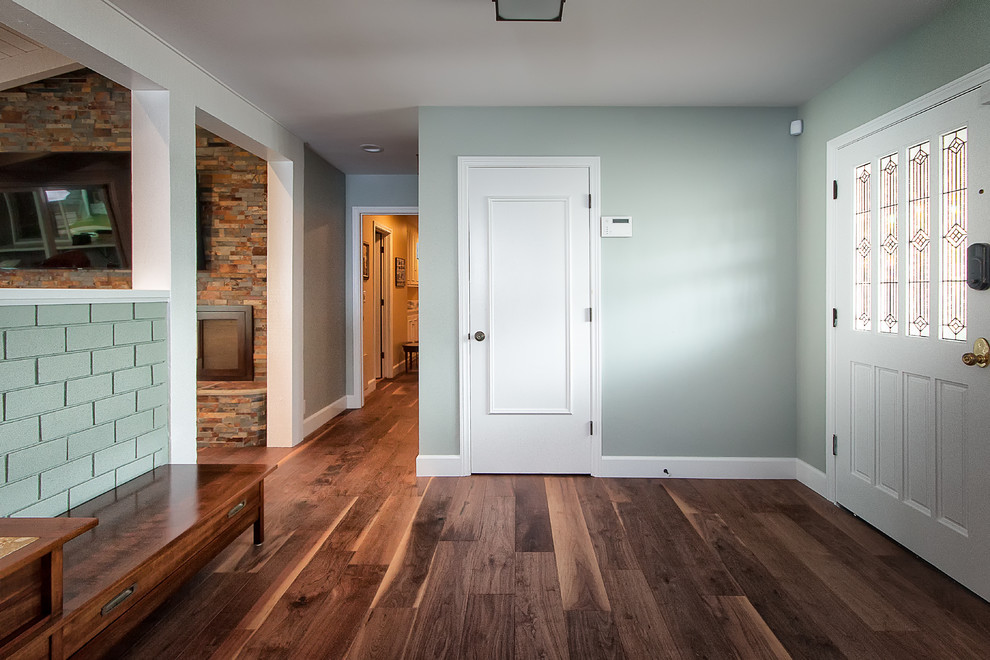 Réalisation d'un hall d'entrée tradition de taille moyenne avec un mur gris, un sol en bois brun, une porte blanche et une porte simple.
