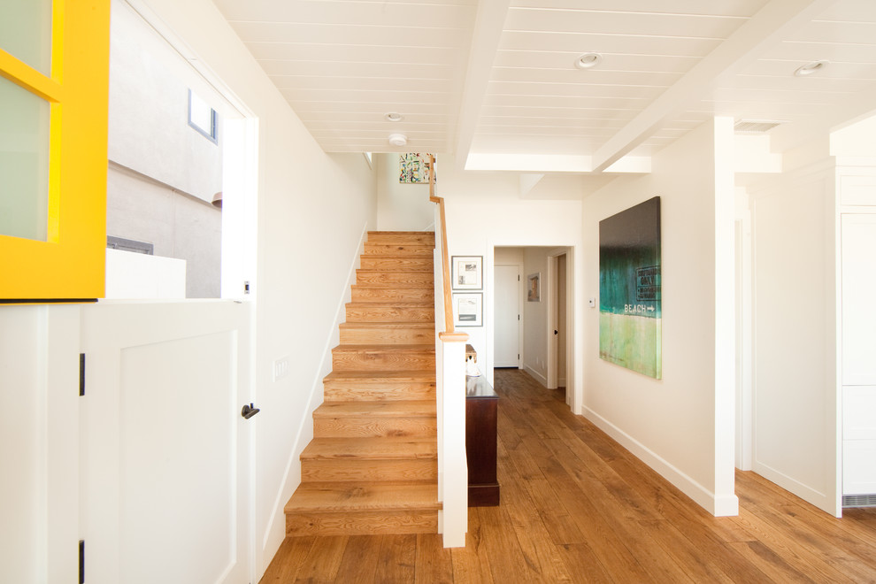 Example of a mid-sized beach style light wood floor and brown floor entryway design in Orange County with white walls and a white front door
