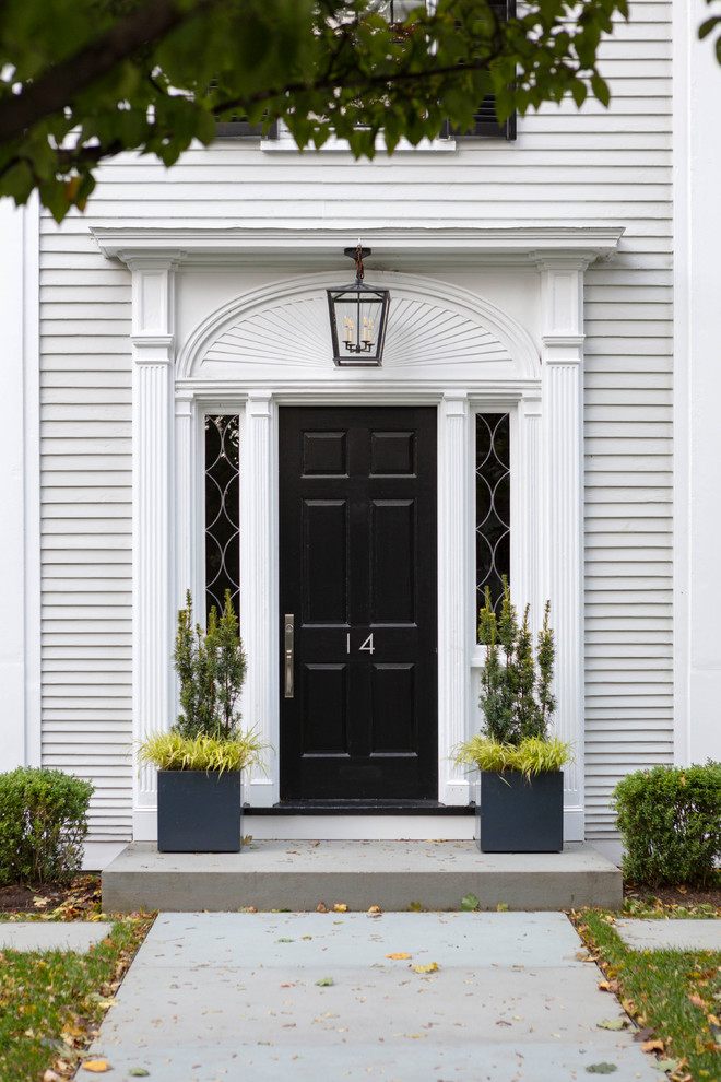 Пример оригинального дизайна: входная дверь в классическом стиле с белыми стенами, бетонным полом, одностворчатой входной дверью, черной входной дверью и серым полом
