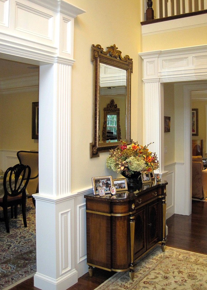 Immagine di un grande ingresso chic con pareti bianche, pavimento in legno massello medio e pavimento marrone