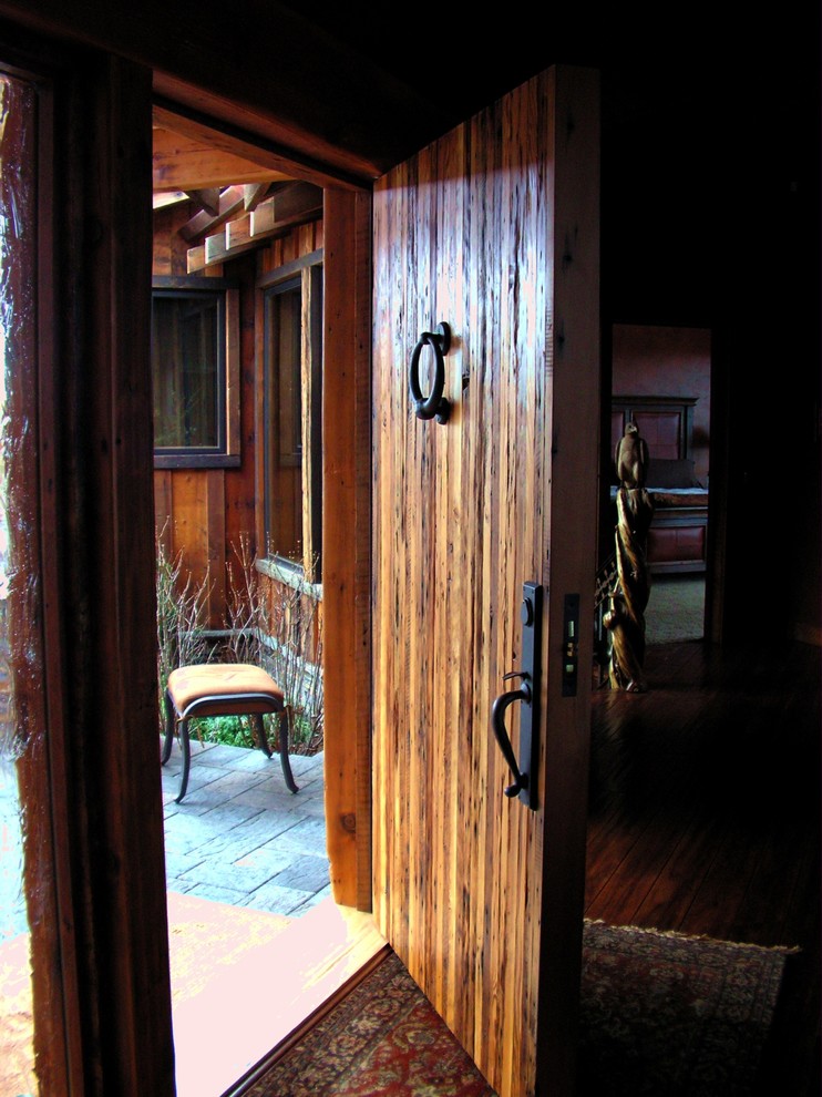 Immagine di un'ampia porta d'ingresso rustica con pareti marroni, pavimento in legno massello medio, una porta a pivot e una porta in legno bruno