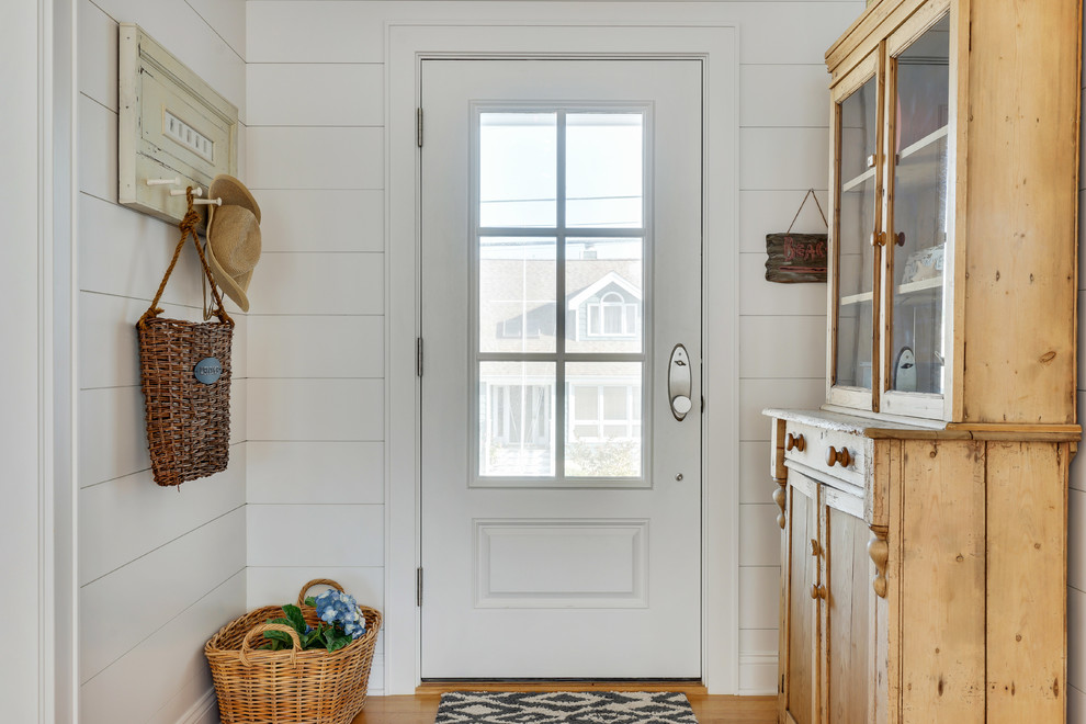 На фото: входная дверь в морском стиле с белыми стенами, светлым паркетным полом, одностворчатой входной дверью и белой входной дверью с