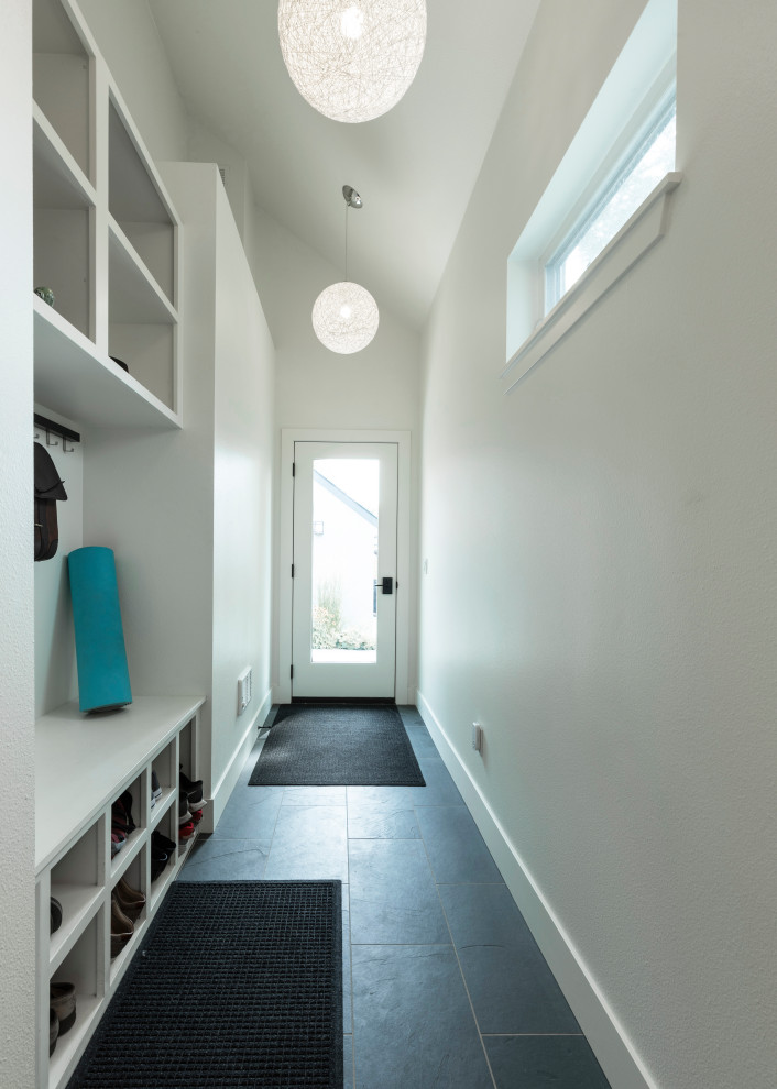 Cette image montre une petite entrée design avec un vestiaire, un mur blanc, un plafond voûté, un sol en ardoise et un sol gris.