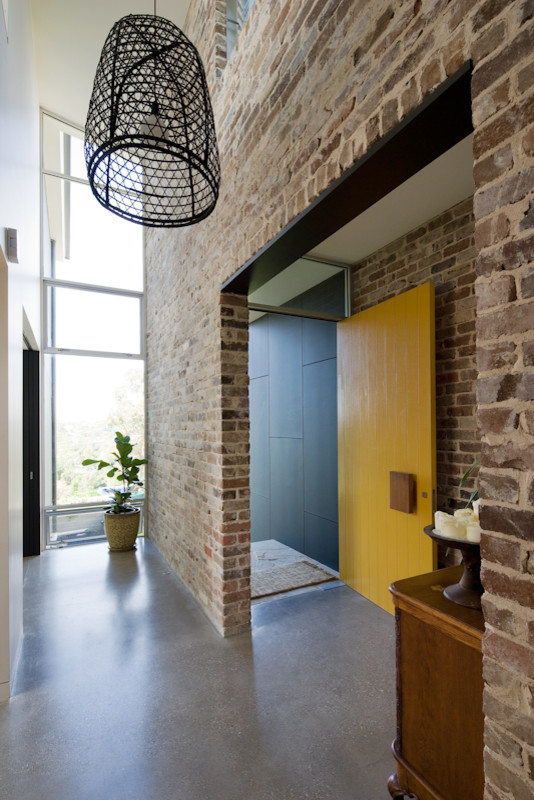 Cette photo montre une porte d'entrée tendance de taille moyenne avec sol en béton ciré, une porte pivot et une porte jaune.