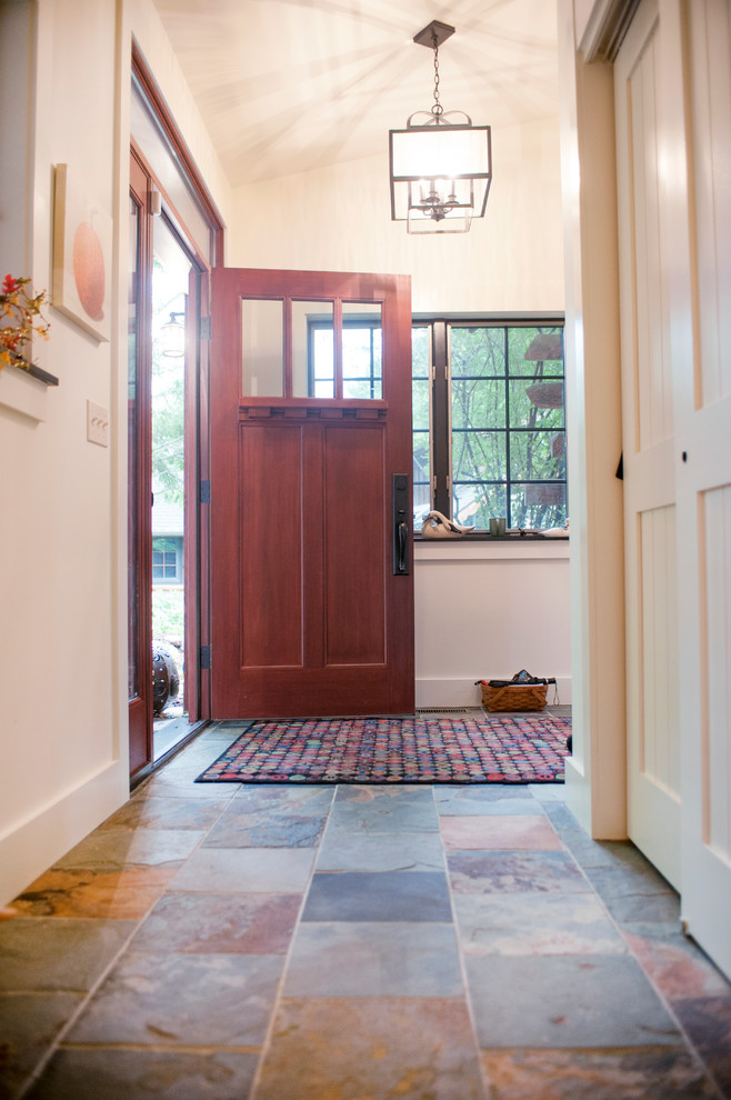 Réalisation d'une entrée chalet de taille moyenne avec un vestiaire, un mur blanc, un sol en ardoise, une porte simple et une porte rouge.