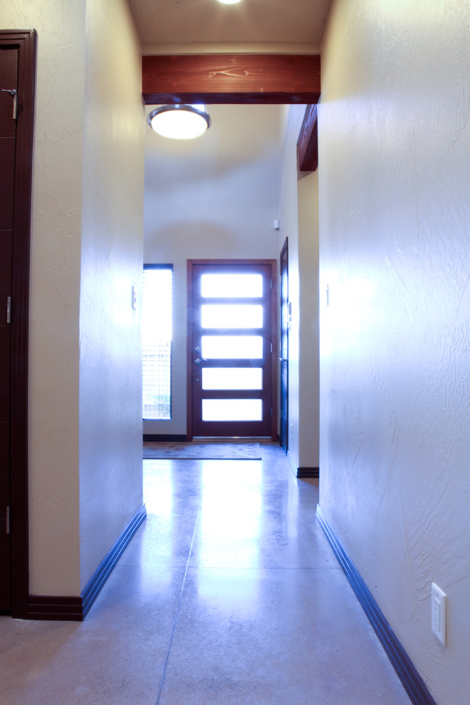 Photo of a medium sized contemporary front door in Albuquerque with beige walls, concrete flooring, a single front door and a dark wood front door.