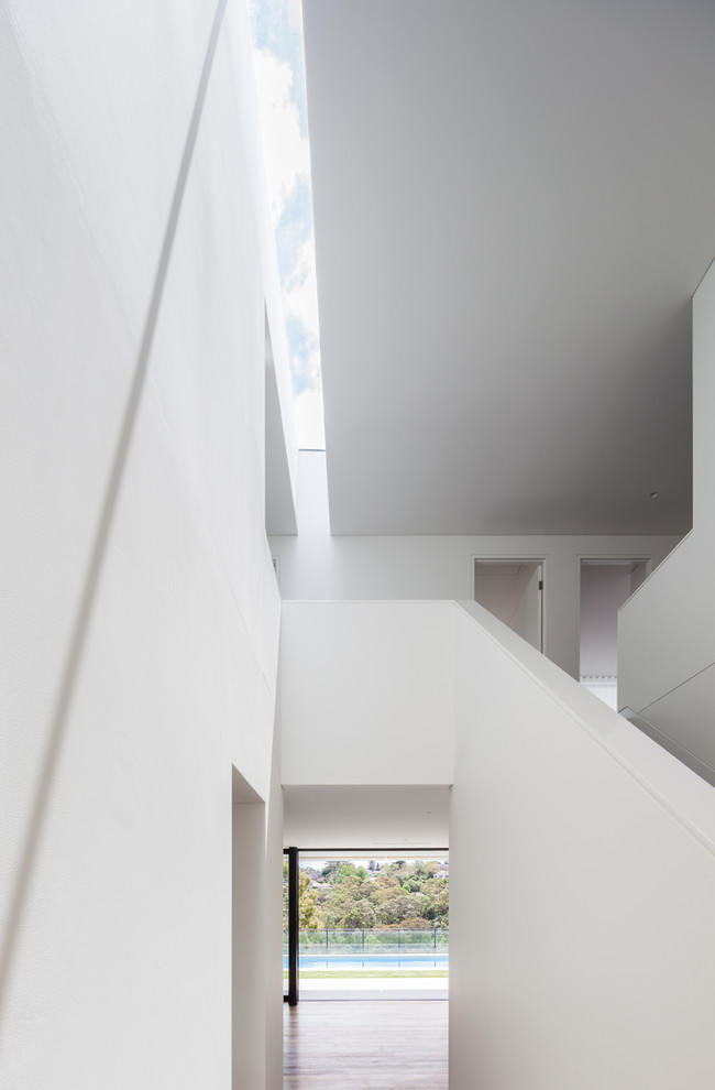 Ispirazione per un ingresso o corridoio minimalista di medie dimensioni con pareti bianche, pavimento in legno massello medio e una porta singola