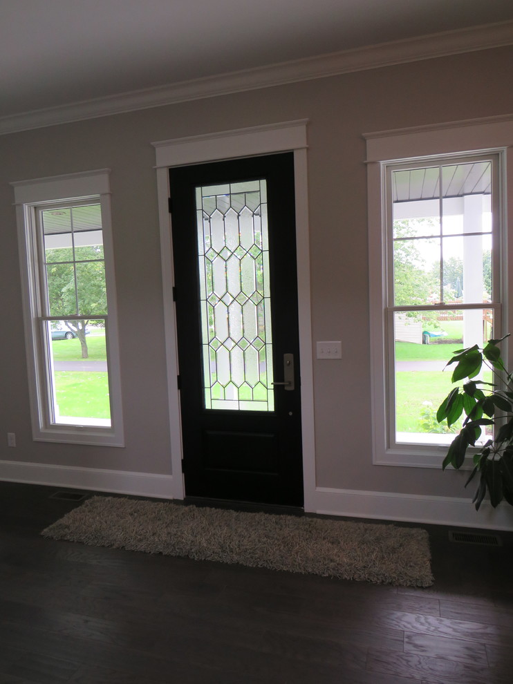 Modelo de puerta principal campestre grande con paredes beige, suelo de madera oscura, puerta simple y puerta de madera oscura
