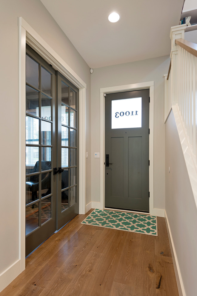 Großes Modernes Foyer mit grauer Wandfarbe, braunem Holzboden, Drehtür und grauer Haustür in Seattle