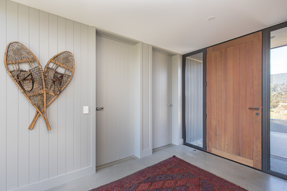 Exemple d'un hall d'entrée nature avec un mur gris, sol en béton ciré, une porte simple, une porte en bois brun et un sol gris.