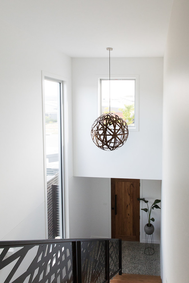 Réalisation d'une porte d'entrée minimaliste de taille moyenne avec un mur blanc, un sol en liège, une porte simple, une porte en bois brun et un sol gris.