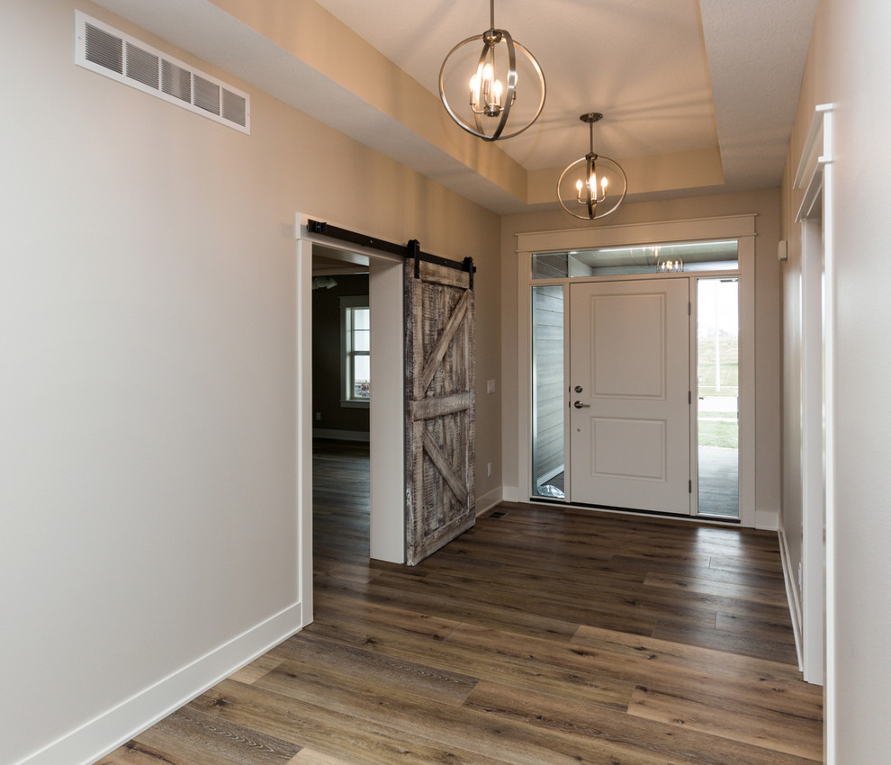 Ejemplo de distribuidor de estilo de casa de campo con paredes blancas, suelo vinílico, puerta simple, puerta blanca y suelo marrón