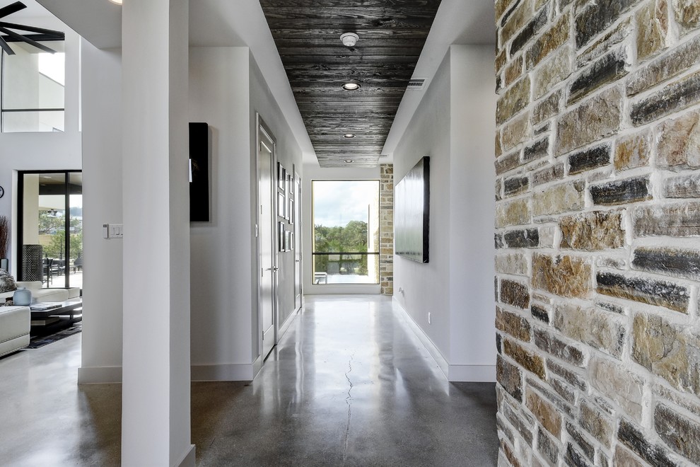 Foto de distribuidor actual grande con paredes blancas, suelo de cemento, puerta pivotante y suelo gris