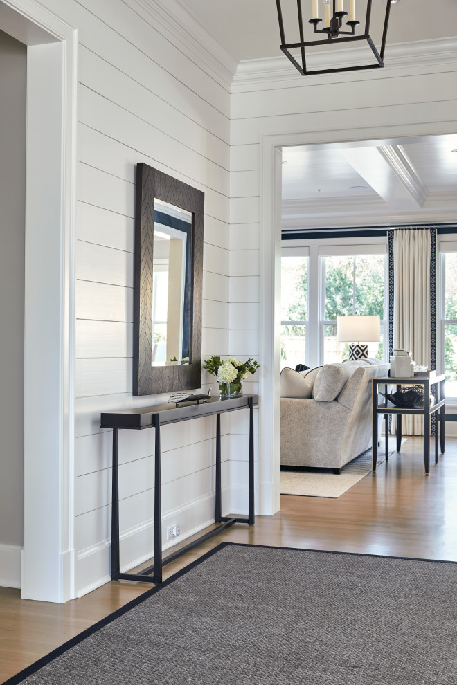 Imagen de hall campestre de tamaño medio con paredes blancas, suelo de madera clara, puerta simple, puerta negra, suelo beige y machihembrado