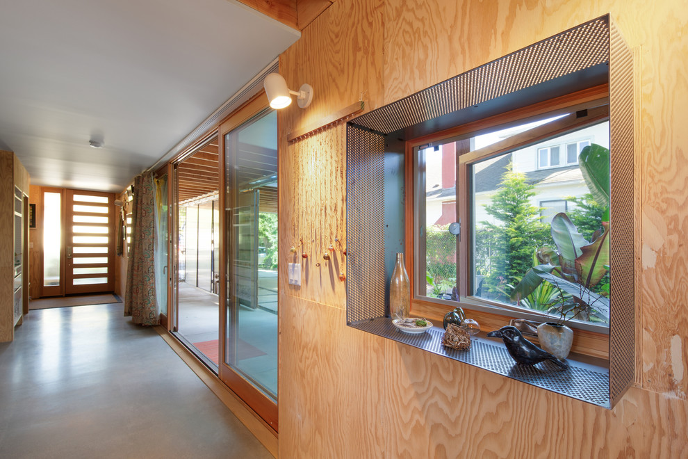 Cette photo montre une entrée tendance avec un couloir, sol en béton ciré et une porte en bois brun.