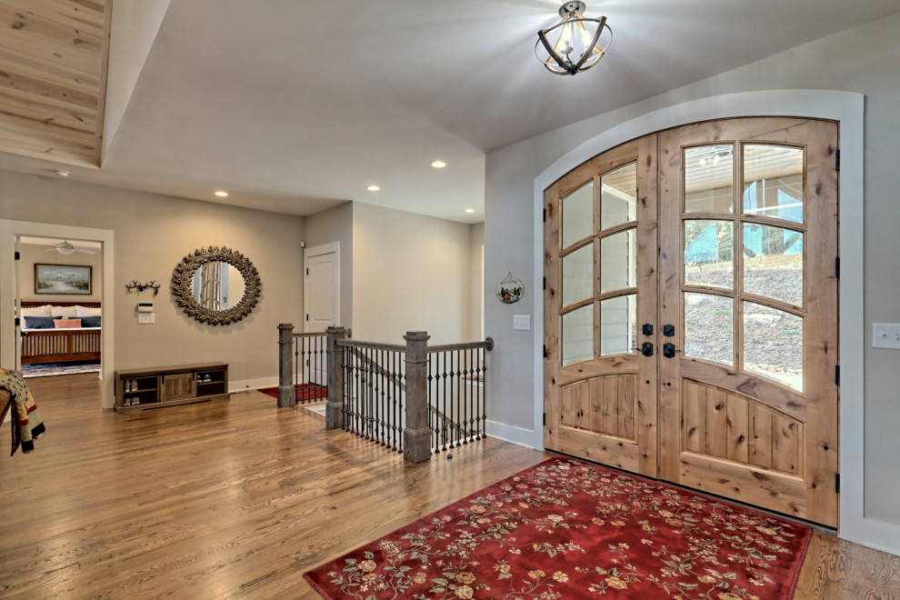 Ejemplo de puerta principal de estilo americano grande con paredes grises, suelo de madera en tonos medios, puerta doble, puerta de madera clara y suelo marrón