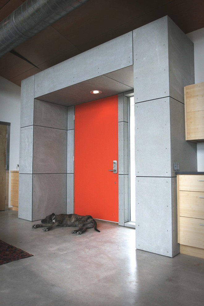 Esempio di un ingresso o corridoio industriale con pavimento in cemento, una porta rossa e pavimento grigio