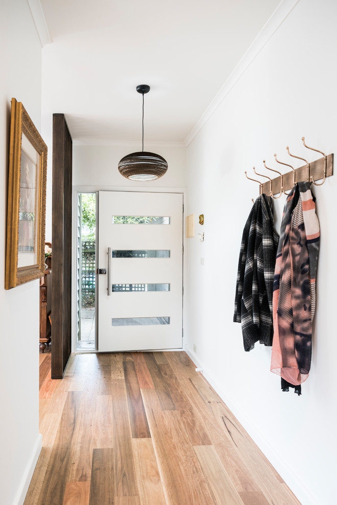 Example of a mid-sized eclectic medium tone wood floor entryway design in Melbourne with white walls and a white front door