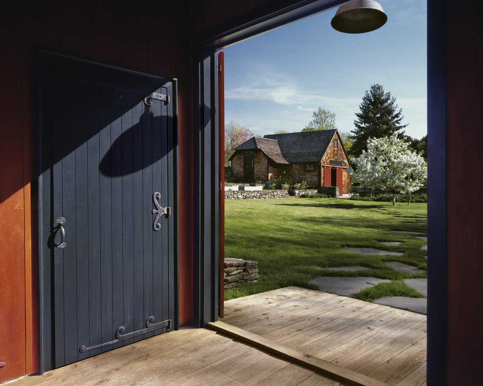 Lantlig inredning av en stor ingång och ytterdörr, med en enkeldörr, en svart dörr, röda väggar och ljust trägolv