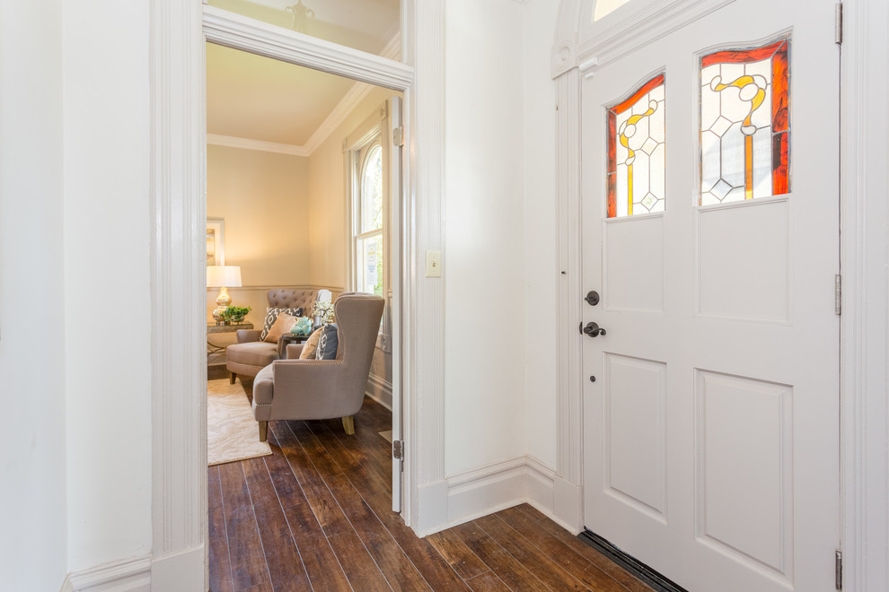 Foto på en liten vintage ingång och ytterdörr, med vita väggar, mörkt trägolv, en enkeldörr, en vit dörr och brunt golv