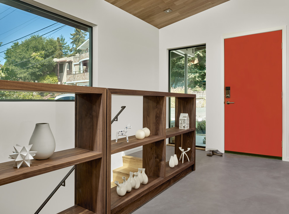 Cette photo montre une entrée rétro de taille moyenne avec un mur blanc, sol en béton ciré, une porte simple et une porte rouge.