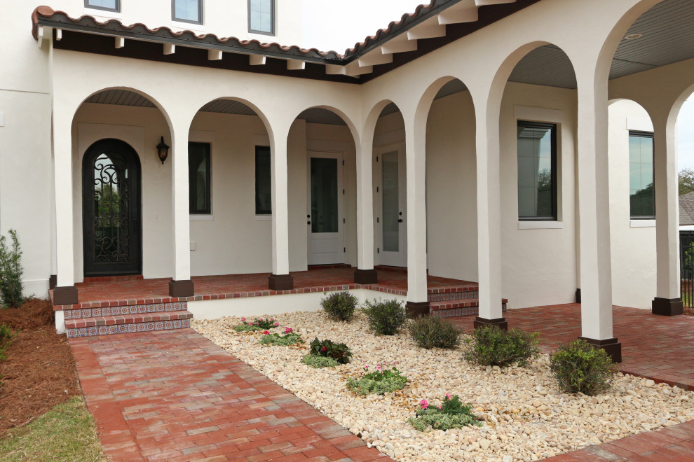 Design ideas for a large mediterranean front door in Orlando with beige walls, brick flooring, a single front door, a dark wood front door and multi-coloured floors.