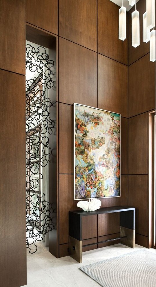На фото: фойе среднего размера в стиле модернизм с коричневыми стенами, полом из известняка, одностворчатой входной дверью, входной дверью из темного дерева и бежевым полом с