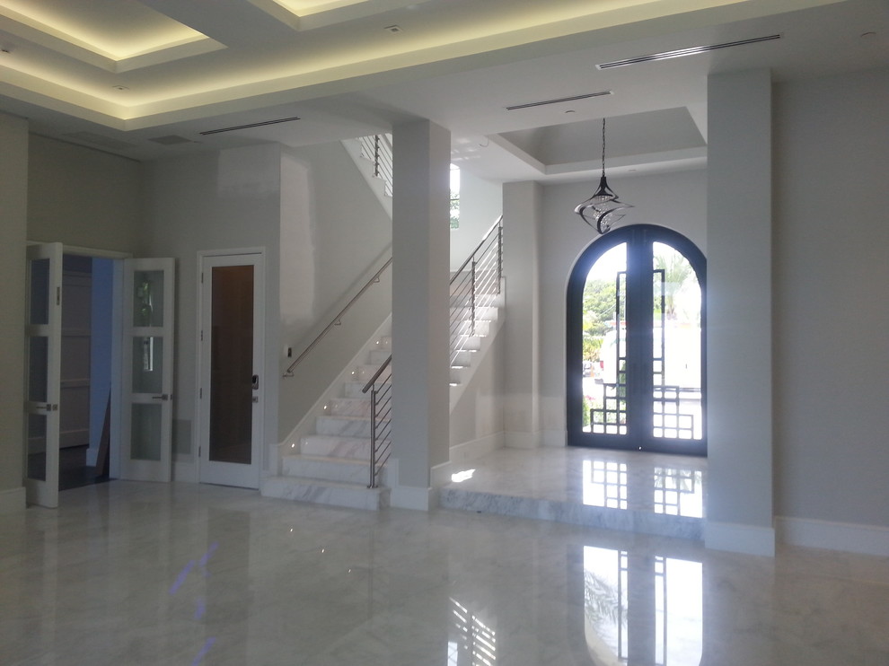 Large transitional marble floor entryway photo in Miami with white walls and a metal front door