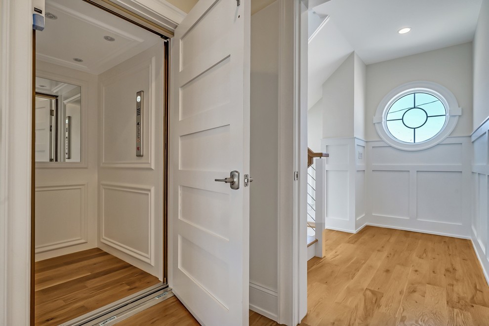 Diseño de hall marinero extra grande con paredes grises, suelo de madera clara, puerta simple y puerta de madera en tonos medios