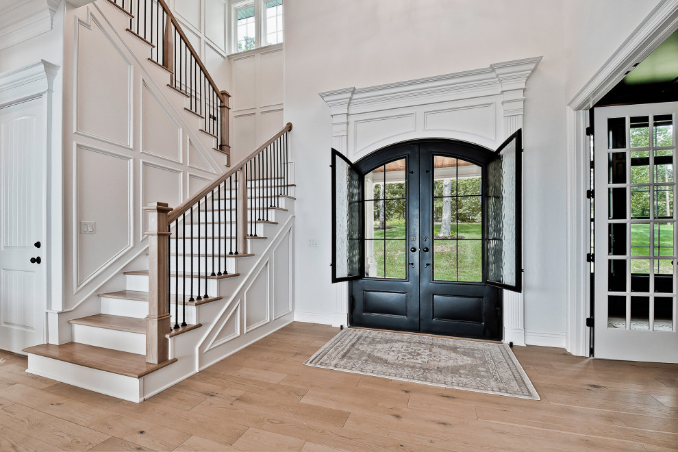 他の地域にあるラグジュアリーな広いトラディショナルスタイルのおしゃれな玄関ドア (白い壁、淡色無垢フローリング、金属製ドア、ベージュの床、板張り壁) の写真