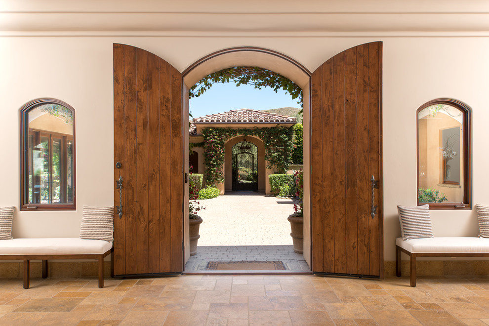 ロサンゼルスにある地中海スタイルのおしゃれな玄関ドア (白い壁、木目調のドア、茶色い床) の写真
