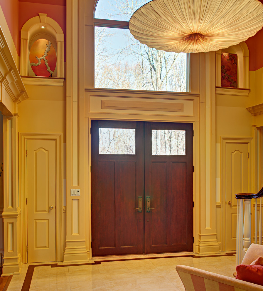 ニューヨークにあるラグジュアリーな広いトランジショナルスタイルのおしゃれな玄関ロビー (黄色い壁、大理石の床、木目調のドア) の写真