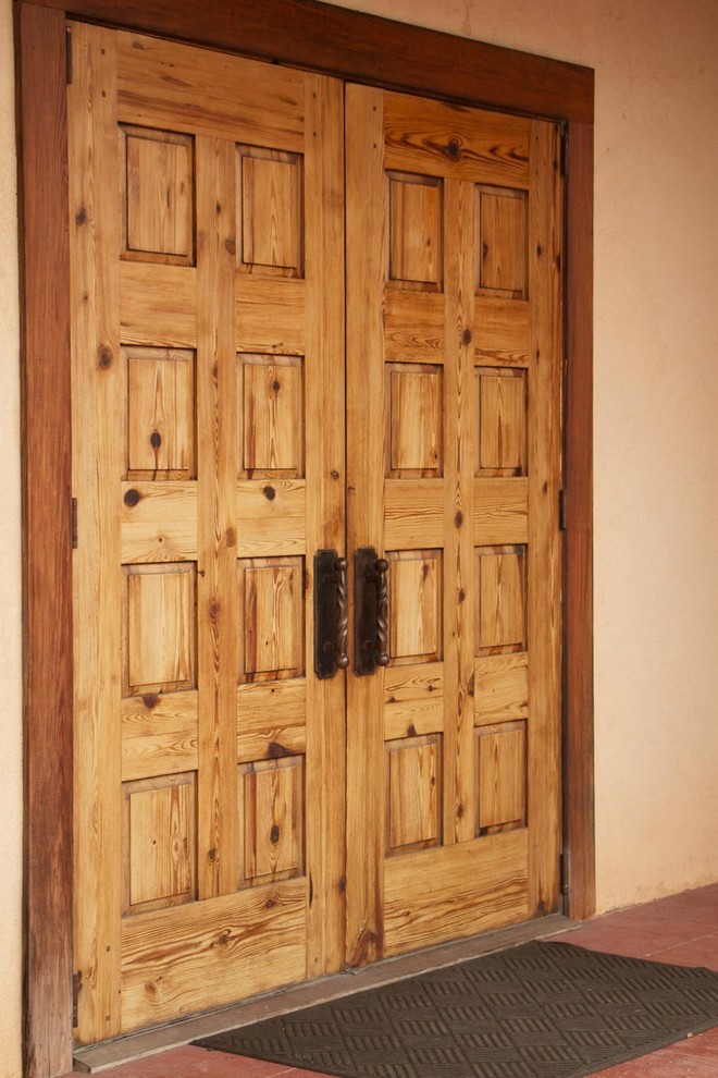 Réalisation d'une entrée champêtre avec un mur beige, une porte double et une porte en bois clair.