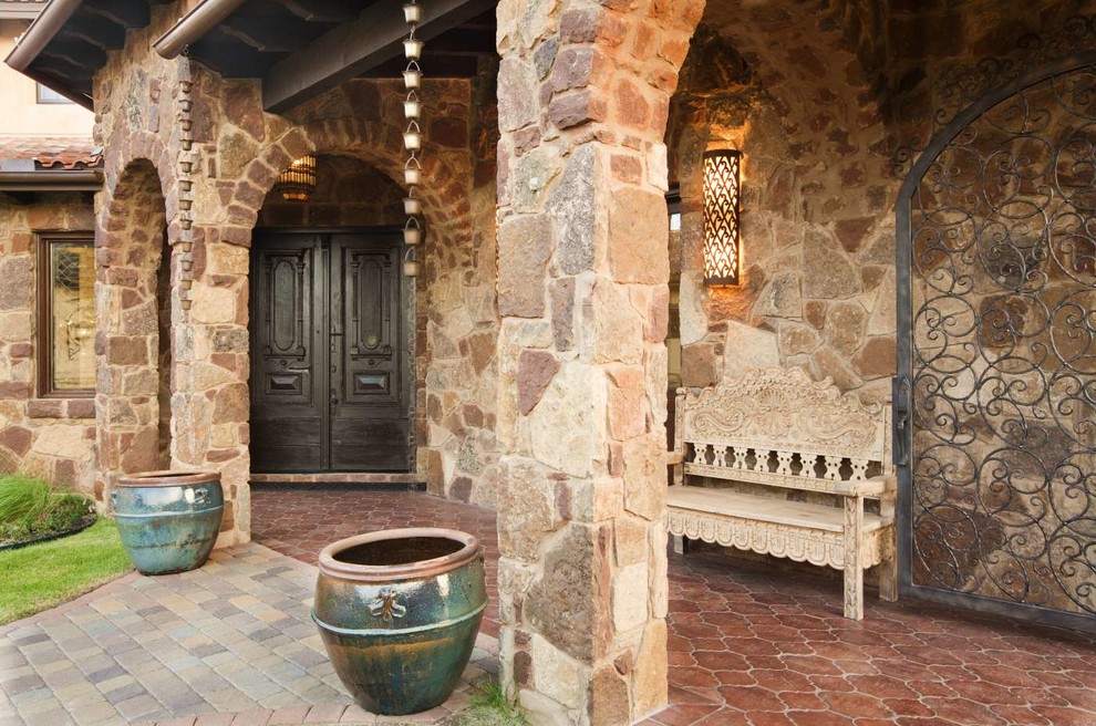 Modelo de puerta principal mediterránea extra grande con paredes beige, suelo de baldosas de terracota, puerta doble, puerta de madera oscura y suelo rojo