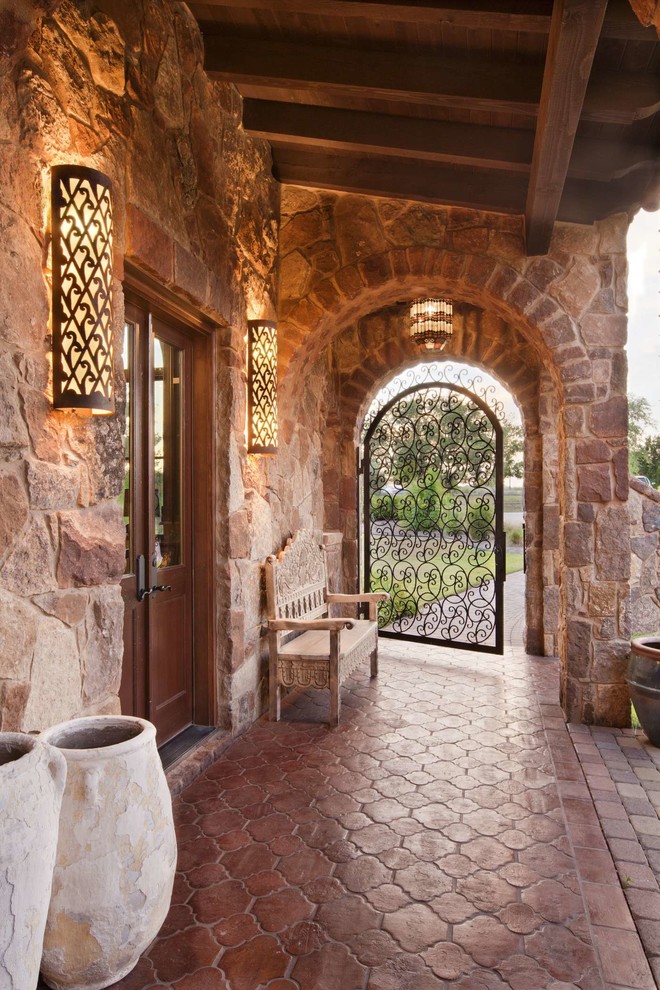 Modelo de puerta principal mediterránea extra grande con paredes beige, suelo de baldosas de terracota, suelo rojo, puerta simple y puerta metalizada