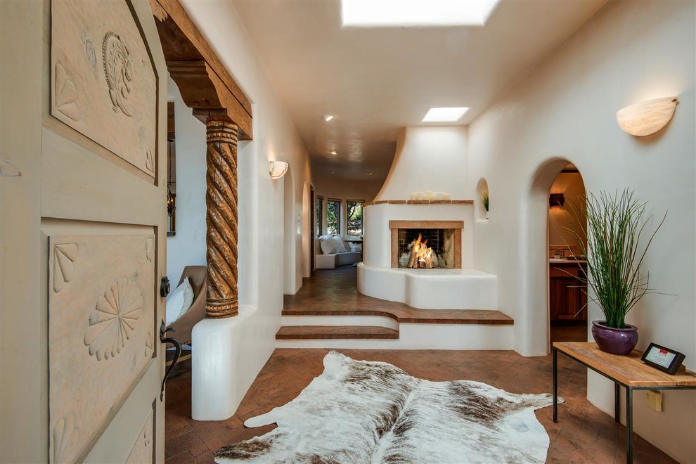 他の地域にある中くらいなサンタフェスタイルのおしゃれな玄関ロビー (白い壁、レンガの床、グレーのドア、茶色い床) の写真