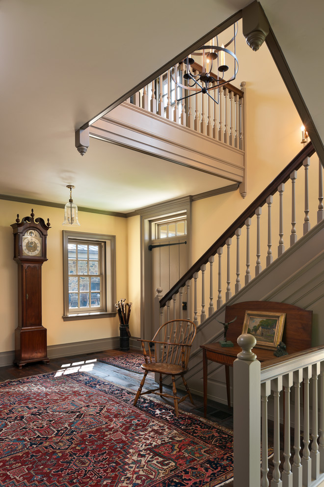 Landhausstil Foyer mit gelber Wandfarbe, dunklem Holzboden, Einzeltür und grauer Haustür in Philadelphia