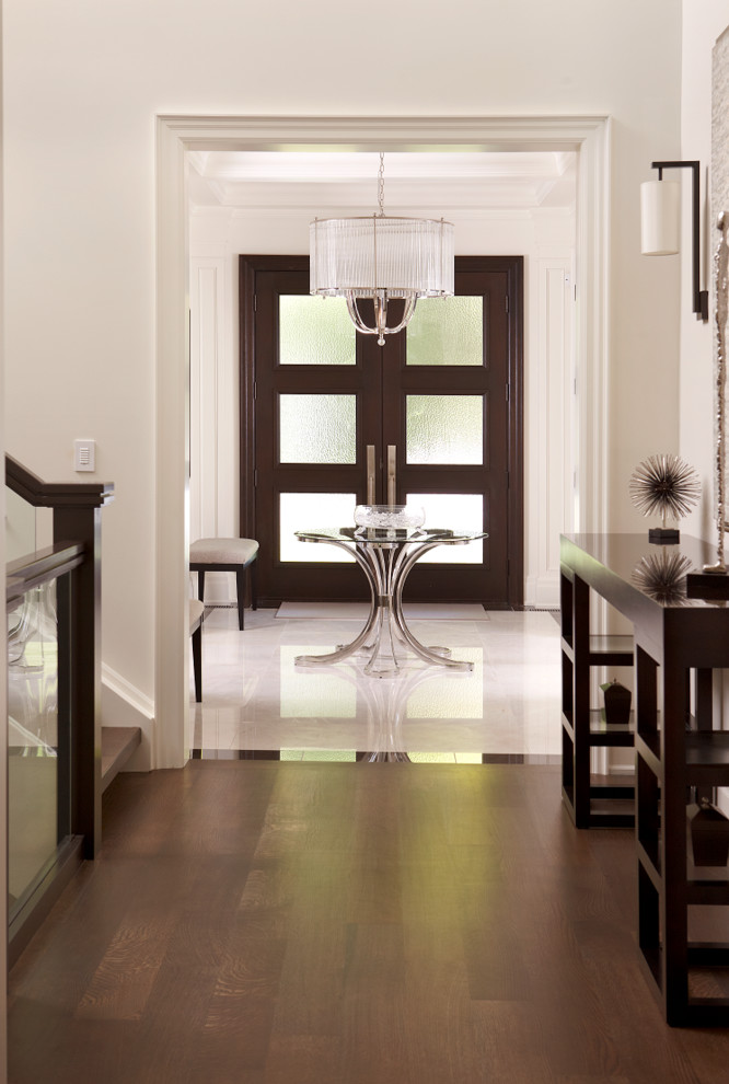 トロントにある中くらいなトランジショナルスタイルのおしゃれな玄関ロビー (白い壁、大理石の床、濃色木目調のドア) の写真