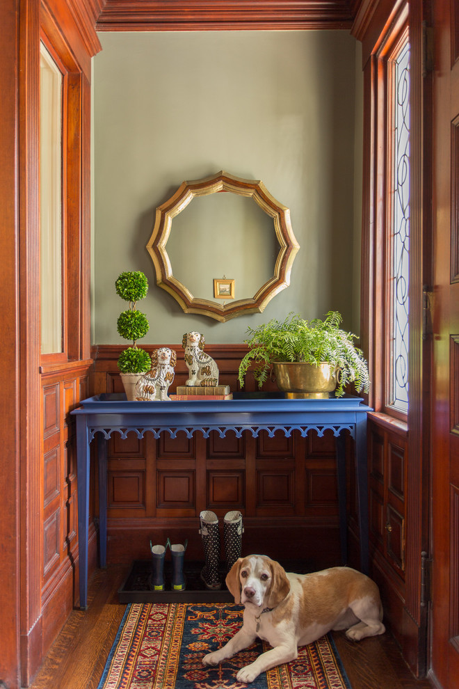 Idée de décoration pour un vestibule tradition avec un mur vert, un sol en bois brun et une porte en bois brun.