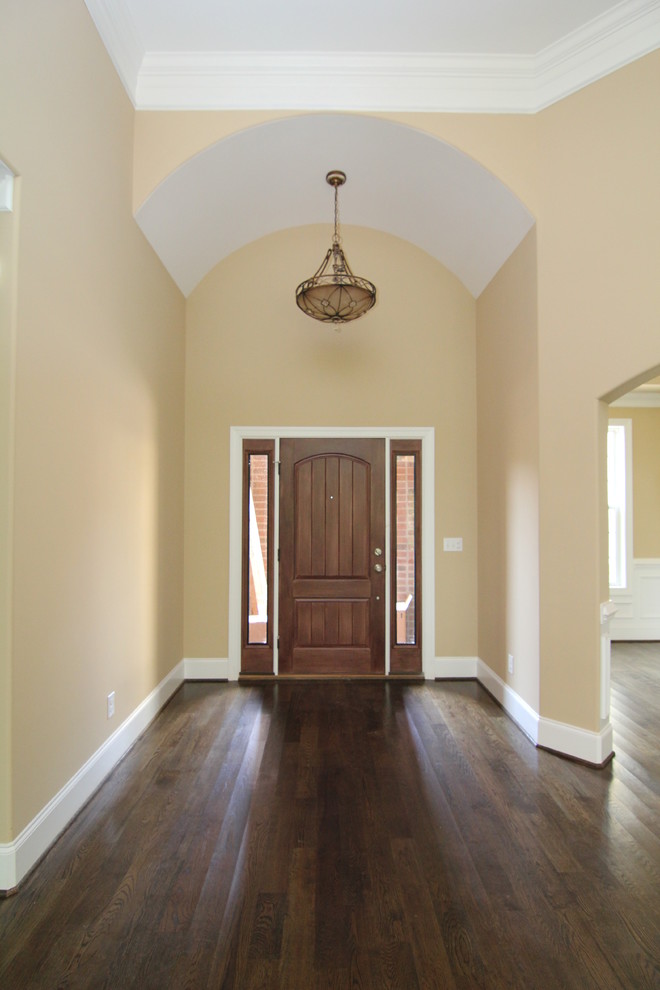 Idee per un grande ingresso chic con pareti beige, parquet scuro, una porta singola e una porta in legno scuro