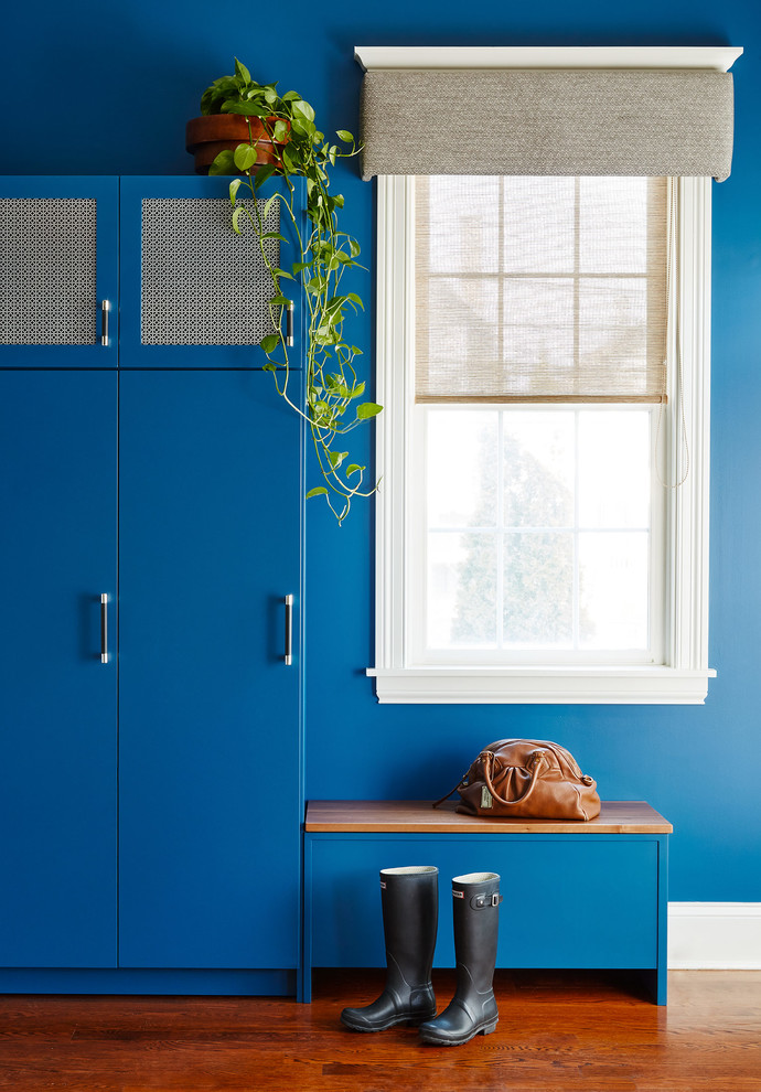 Cette photo montre une entrée éclectique avec un vestiaire, un mur bleu, un sol en bois brun et un sol marron.