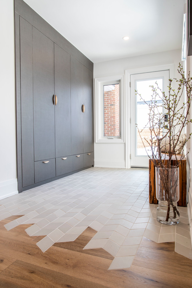 Inspiration pour une entrée design de taille moyenne avec un vestiaire, un mur blanc, un sol en carrelage de porcelaine, une porte simple, une porte blanche et un sol gris.
