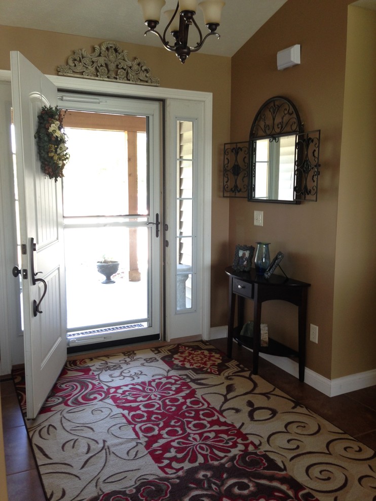 На фото: фойе в классическом стиле с коричневыми стенами, полом из керамической плитки, одностворчатой входной дверью и белой входной дверью с